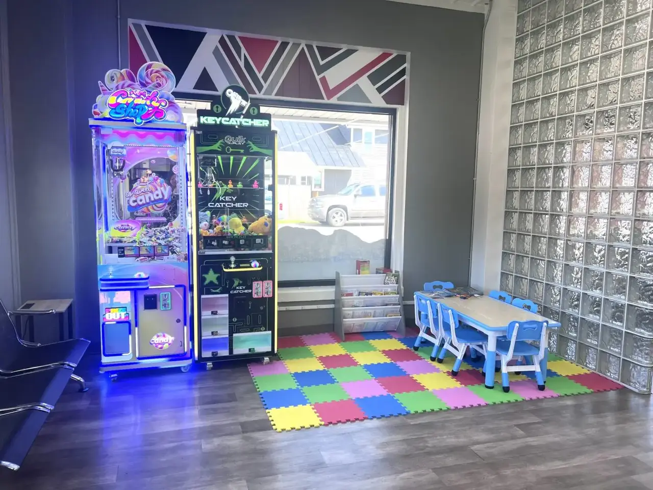 Kids’ play area inside Uptown Laundry featuring arcade-style games and a small table with seating.