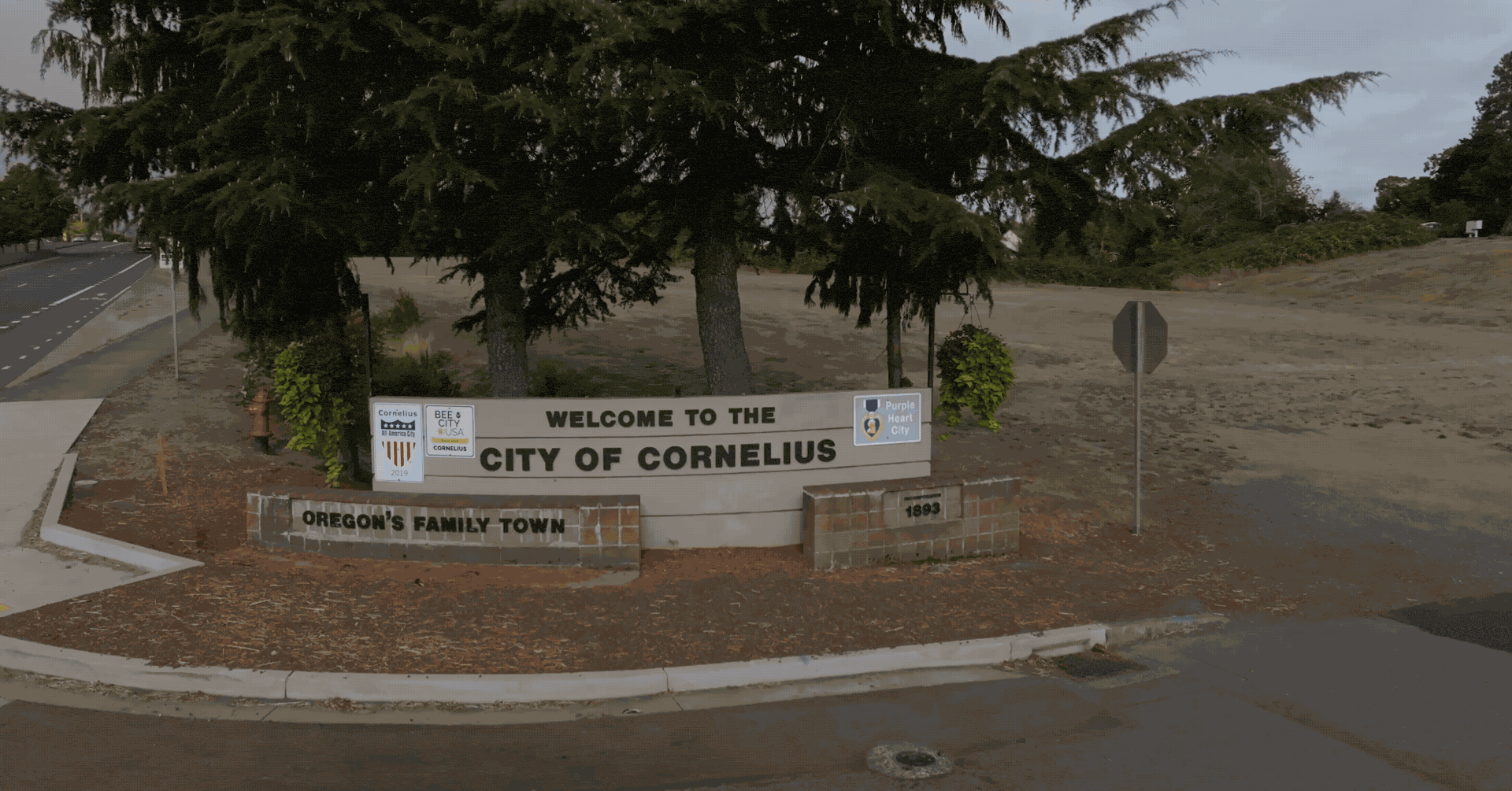 Welcome to the City of Cornelius sign beneath evergreen trees.