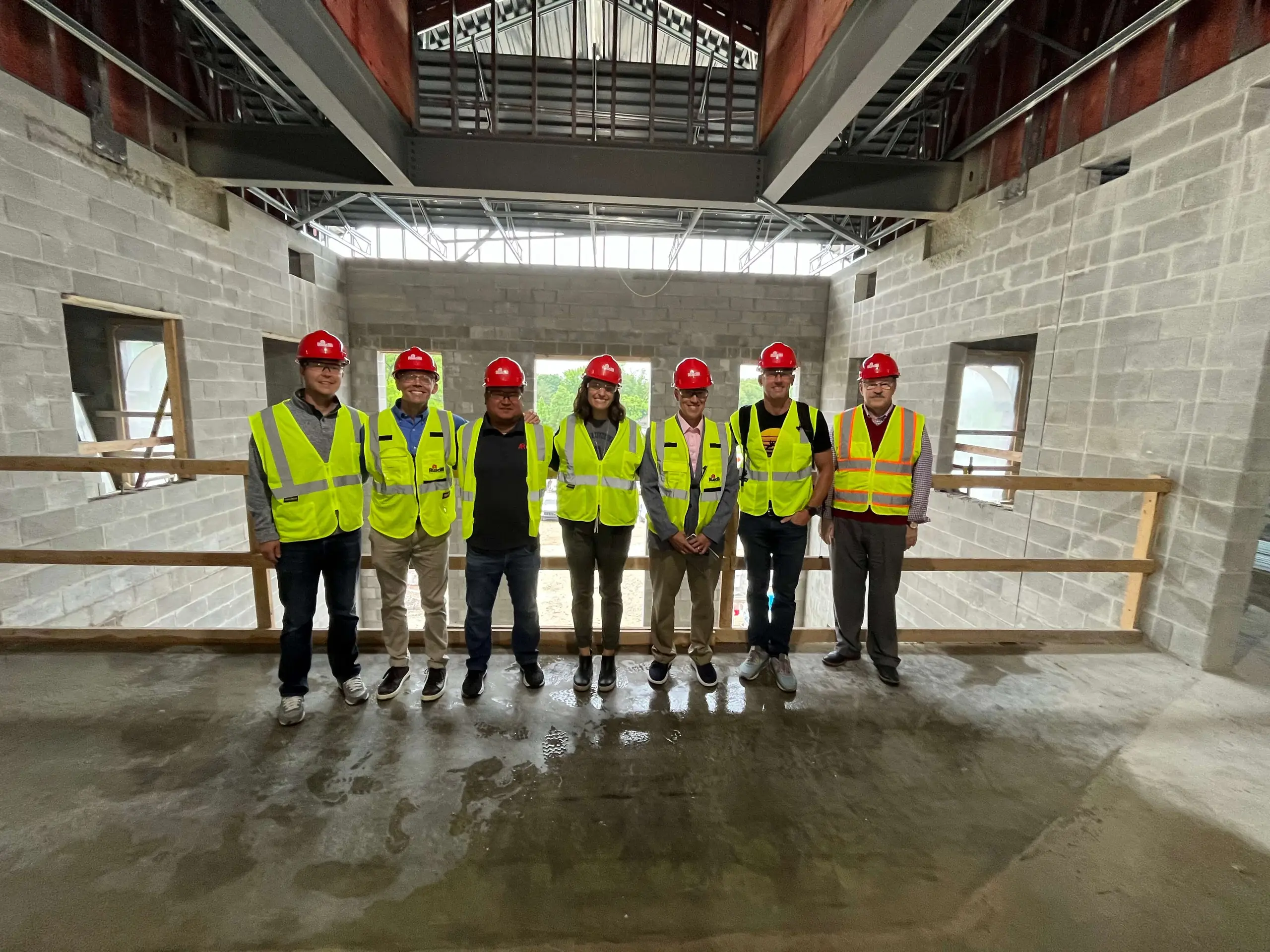 Cohort members in red hard hats touring a school construction site