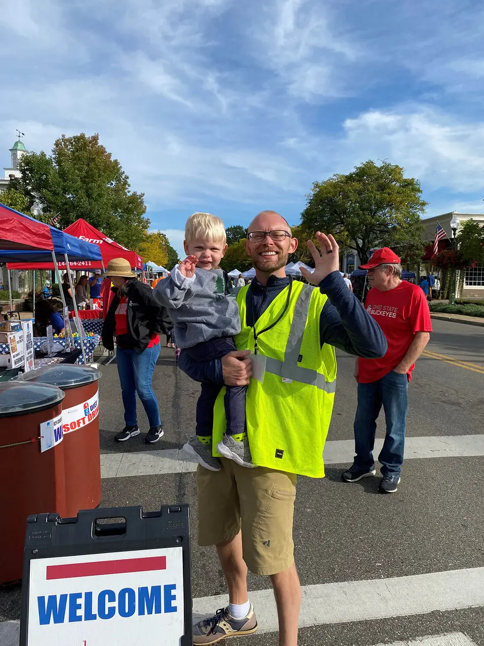 A greeter with a welcome sign meeting families at Market Day