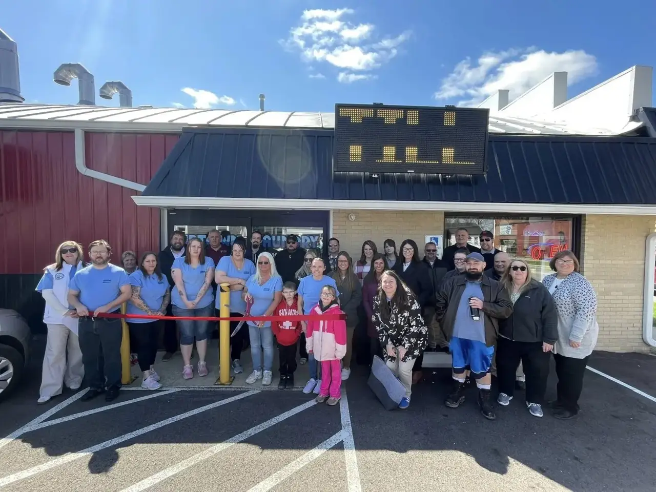 Group gathered outside Uptown Laundry in Bucyrus, Ohio, during the ribbon cutting ceremony celebrating the business’s grand opening.