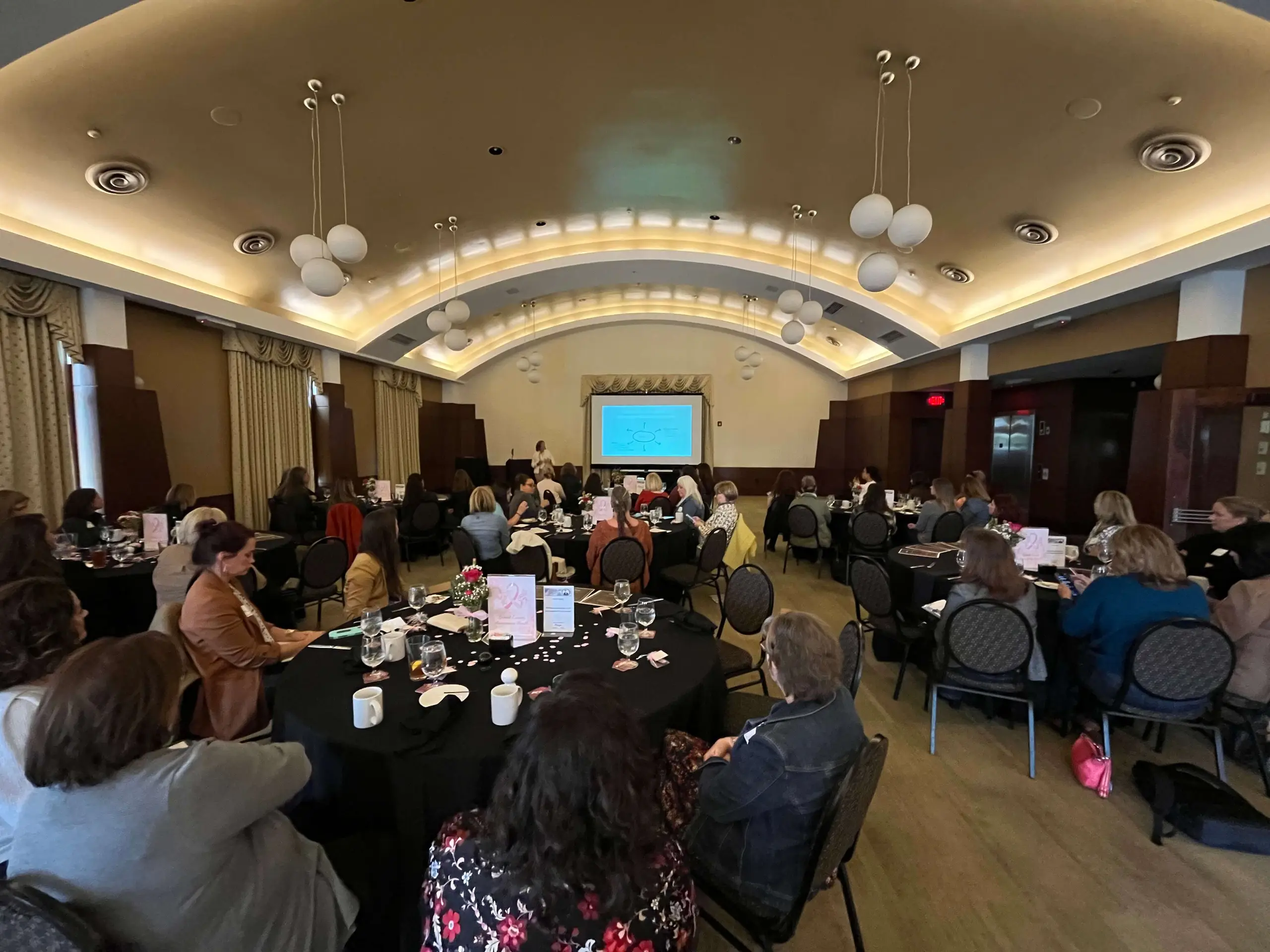 A chamber luncheon under an arched ballroom ceiling