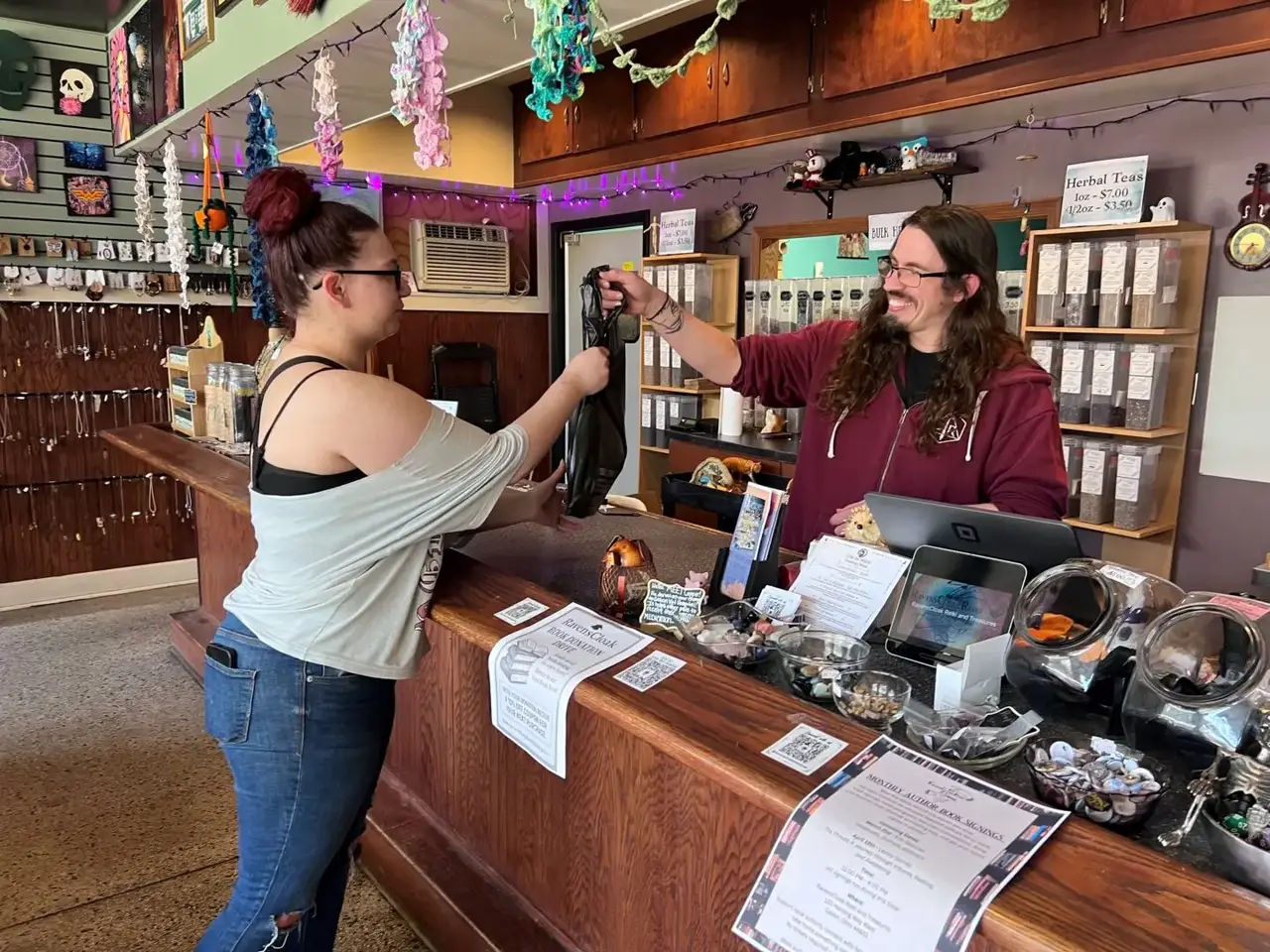 Customer making a purchase at a locally owned shop, exchanging an item across a counter with a store employee