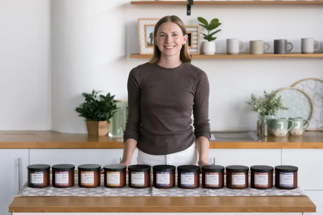 Person standing behind a row of Slower Days Co. candles displayed on a kitchen counter