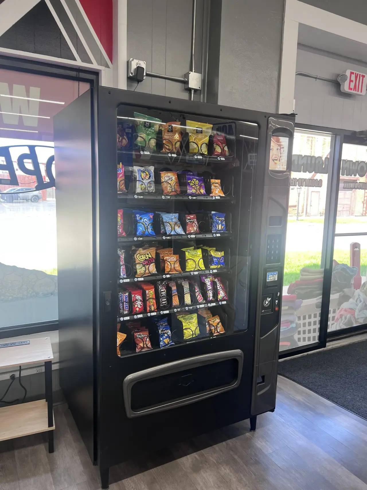 Snack vending machine inside Uptown Laundry offering a variety of snacks while you wait.