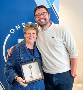 Kathy Williams holding her One Impact Award beside a OneZone representative.
