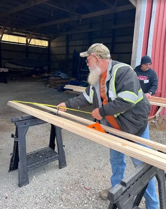 Volunteer measuring wooden boards during a Sleep in Heavenly Peace bed build day.