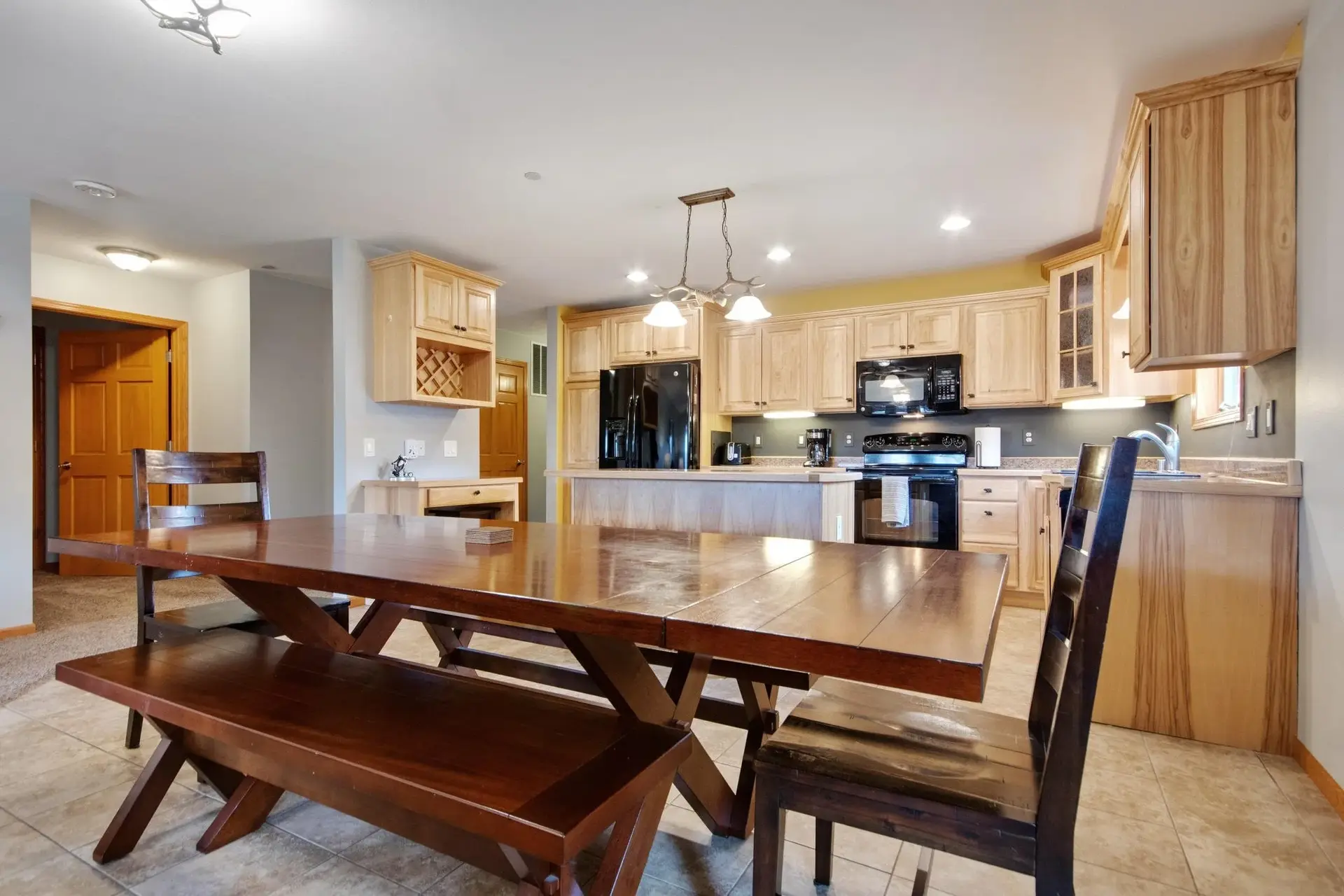Kitchen with wooden cabinets, black appliances, a dining table, and chairs in a well-lit space.