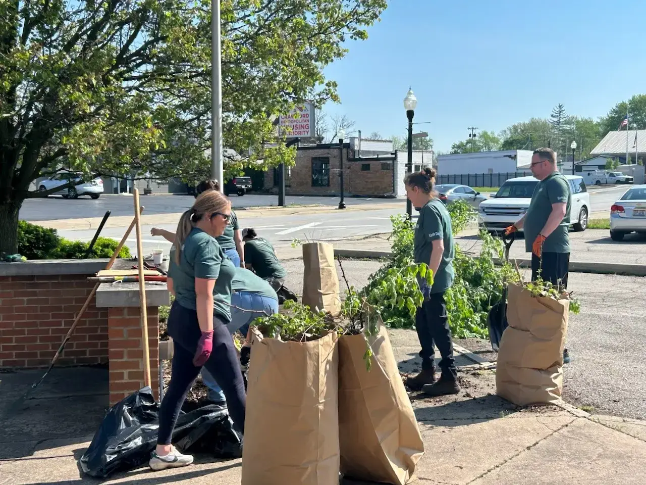 Local business volunteers trimming bushes in Galion, Ohio Arbor Day cleanup event