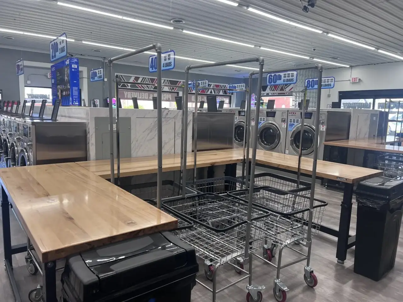 Interior view of Uptown Laundry showing large folding tables and rolling laundry carts for customer use.